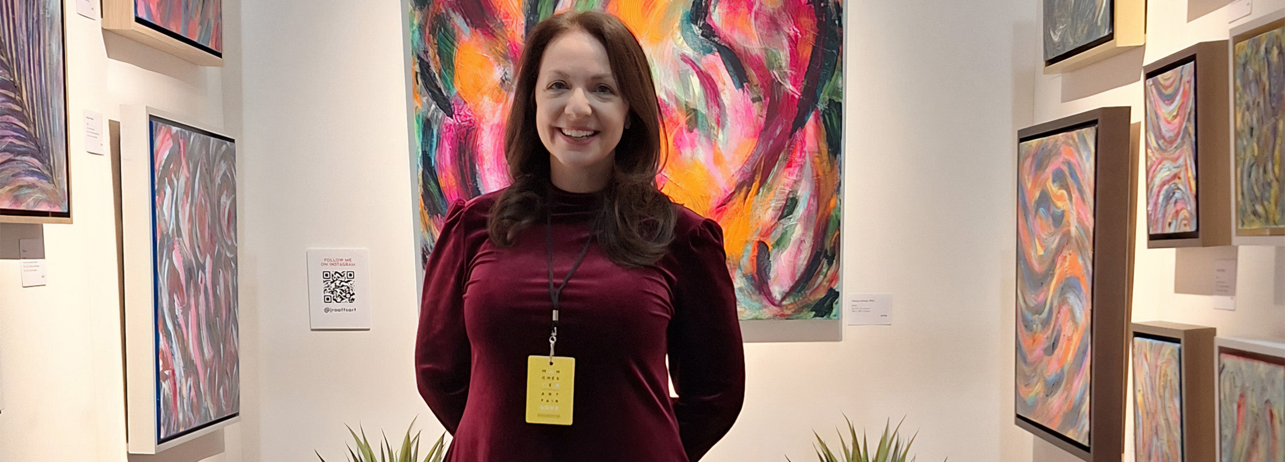 Artist J R Oatts standing in front of a stand of colour abstract art at Manchester Art Fair 2023